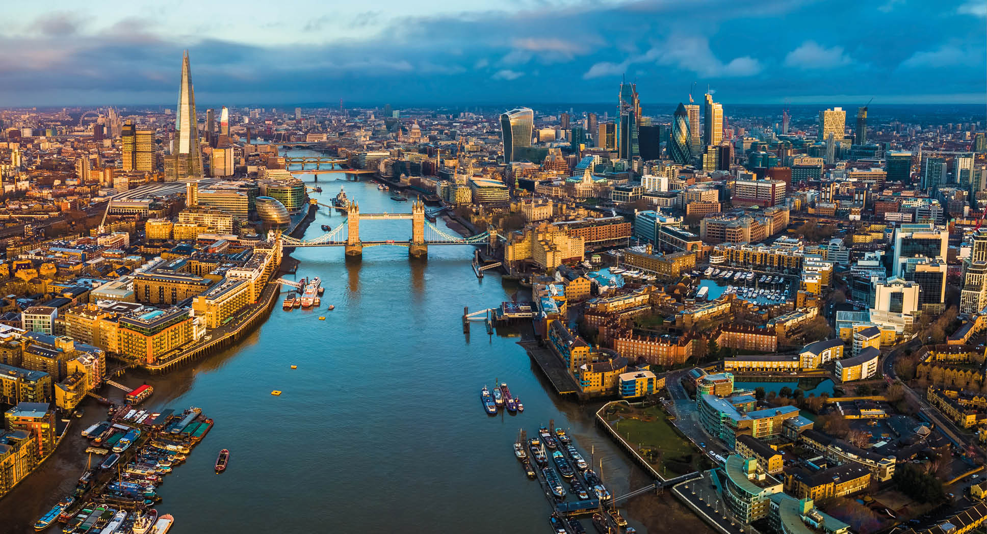 London, England - Panoramic aerial skyline view of London including Tower Bridge with red double-decker bus, Tower of London, skyscrapers of Bank District and other famous skyscrapers at golden hour
