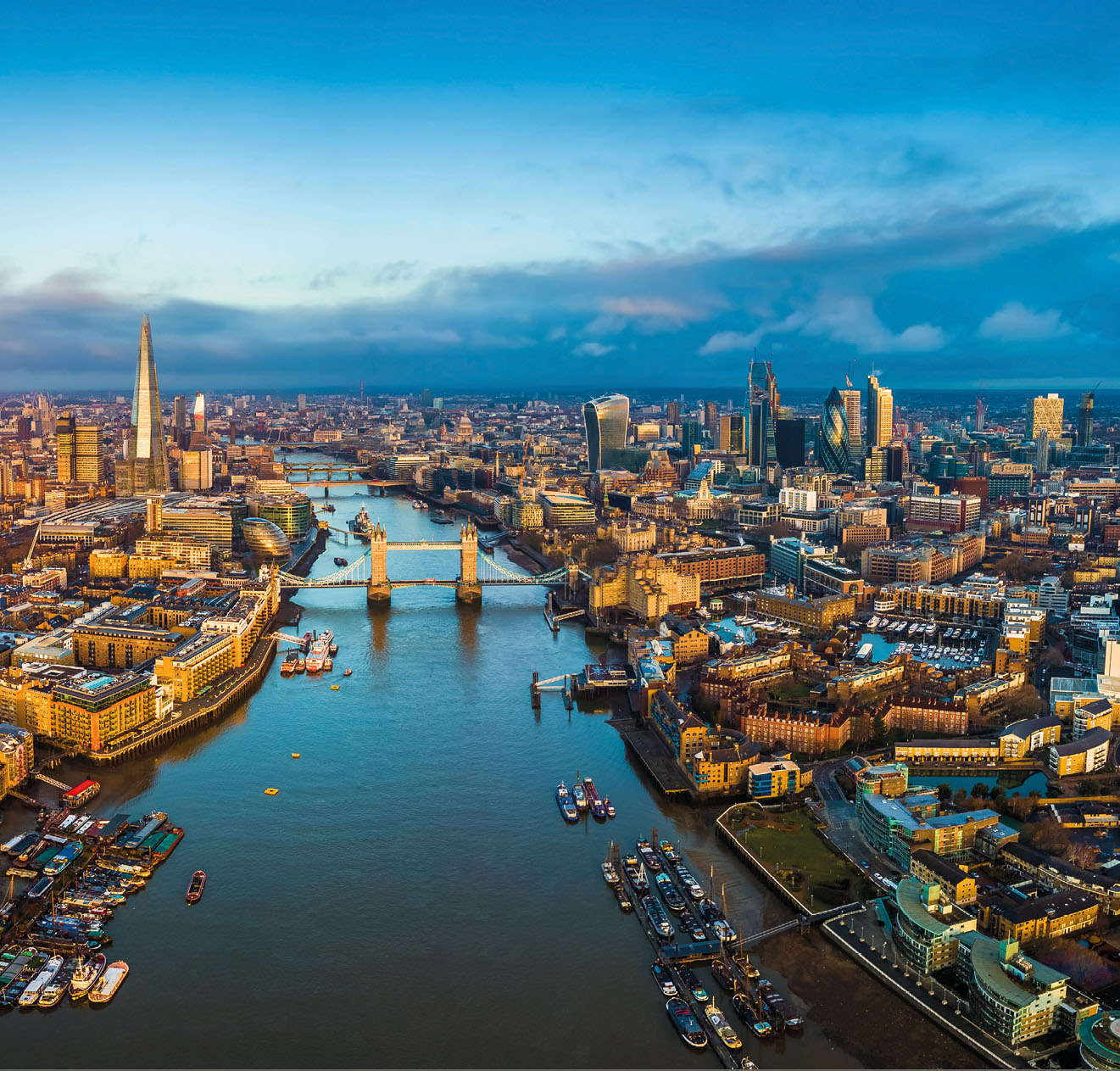 London, England - Panoramic aerial skyline view of London including Tower Bridge with red double-decker bus, Tower of London, skyscrapers of Bank District and other famous skyscrapers at golden hour