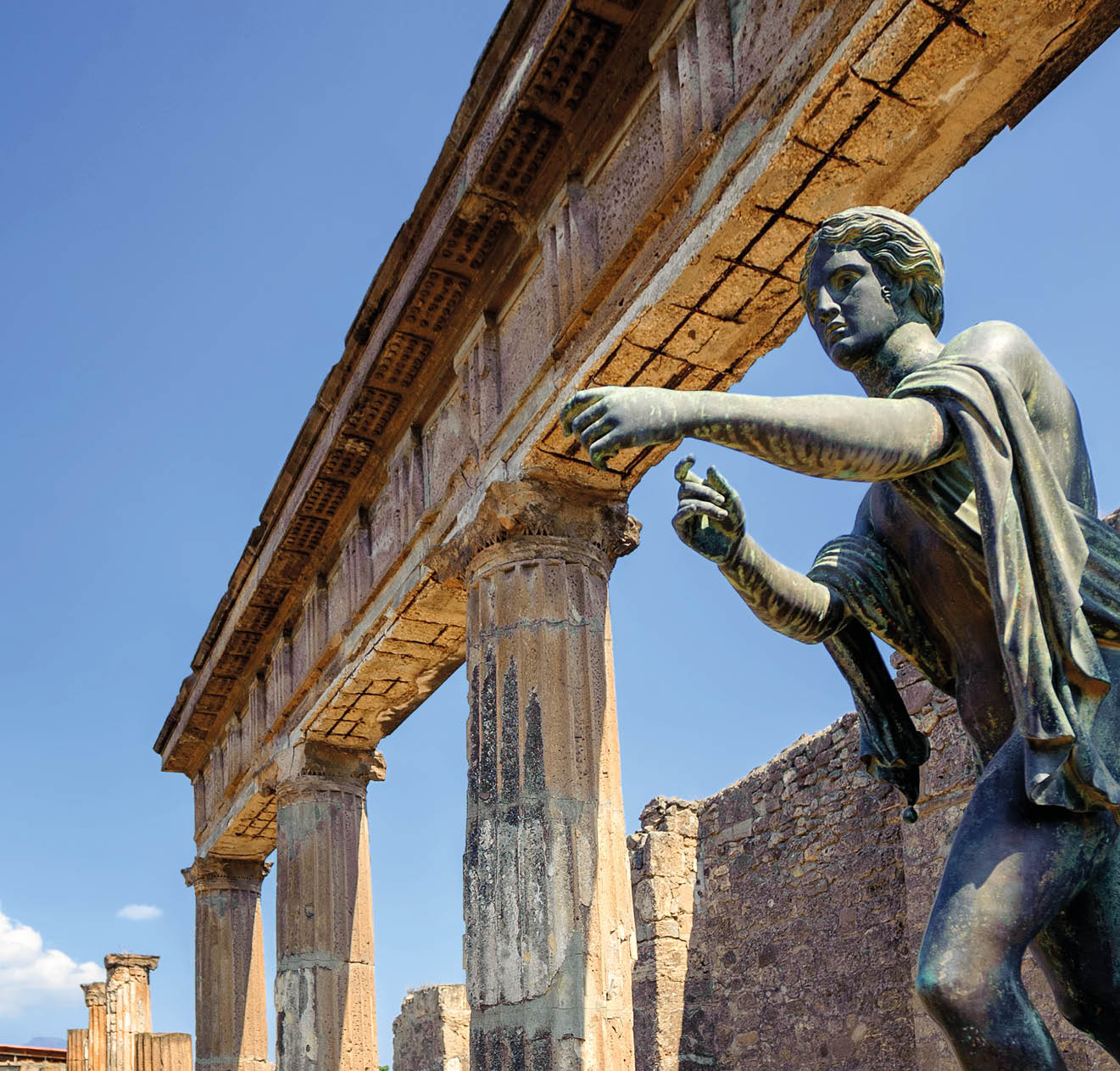 Ruins of the antique Temple of Apollo with bronze Apollo statue in Pompeii, Naples, Italy. Pompeii was destroyed by Vesuvius eruption in 79 AD.