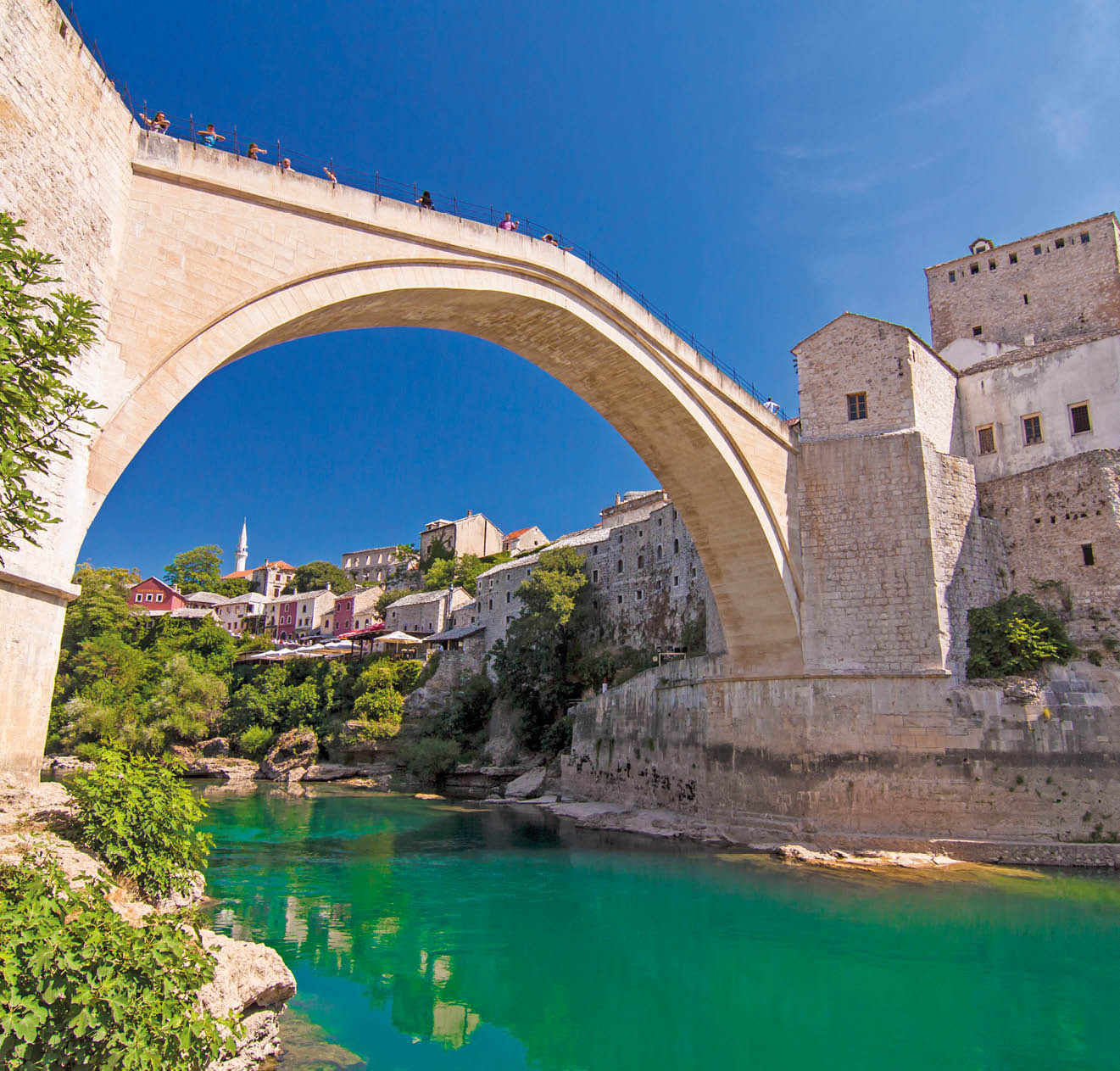 Old Bridge (Stari Most), UNESCO World Heritage, and emerald river Neretva among rocks and old city buildings in summer sun lights. Mostar, Bosnia and Herzegovina