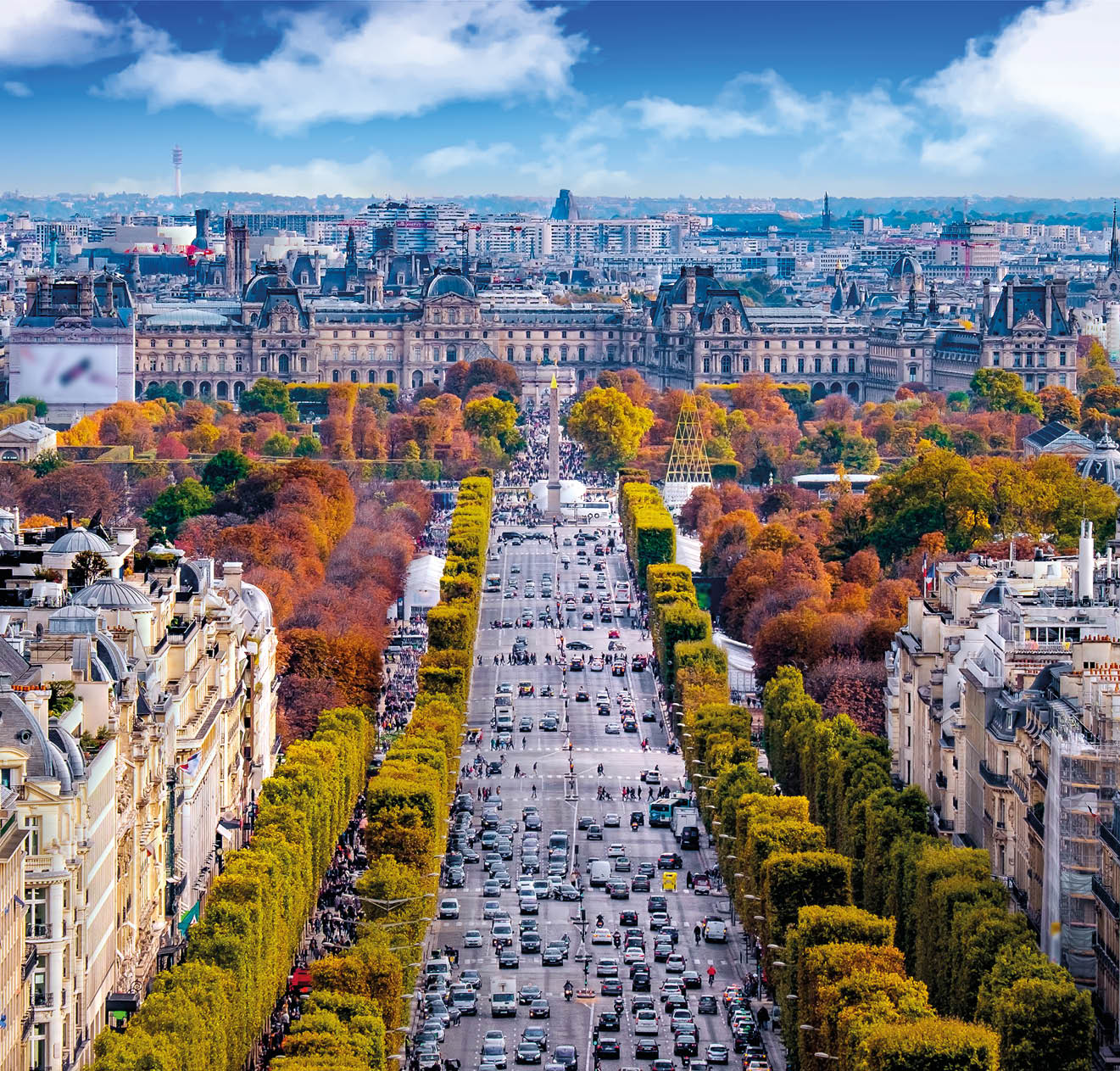 The Avenue des Champs- lys es in late autumn seen from the Arc de Triomphe. Orange and yellow tree leafs with heavy traffic in the middle. Old buildings on both sides.