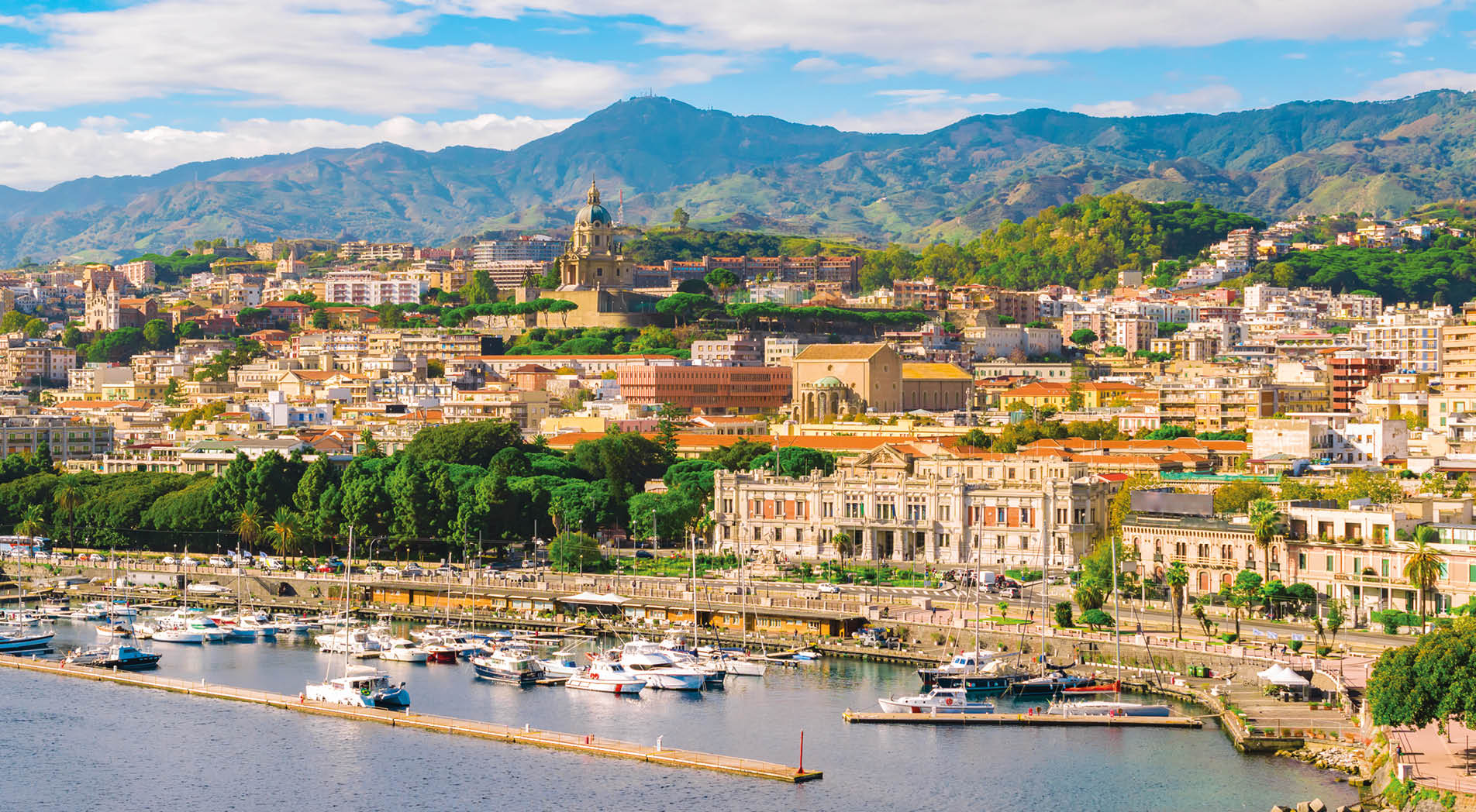 Cityscape of Messina, Sicily, Italy. Multi colored image with buildings, cathedral, mountains, blue sky with clouds, boats and yachts in the harbor or cruise port of Messina.