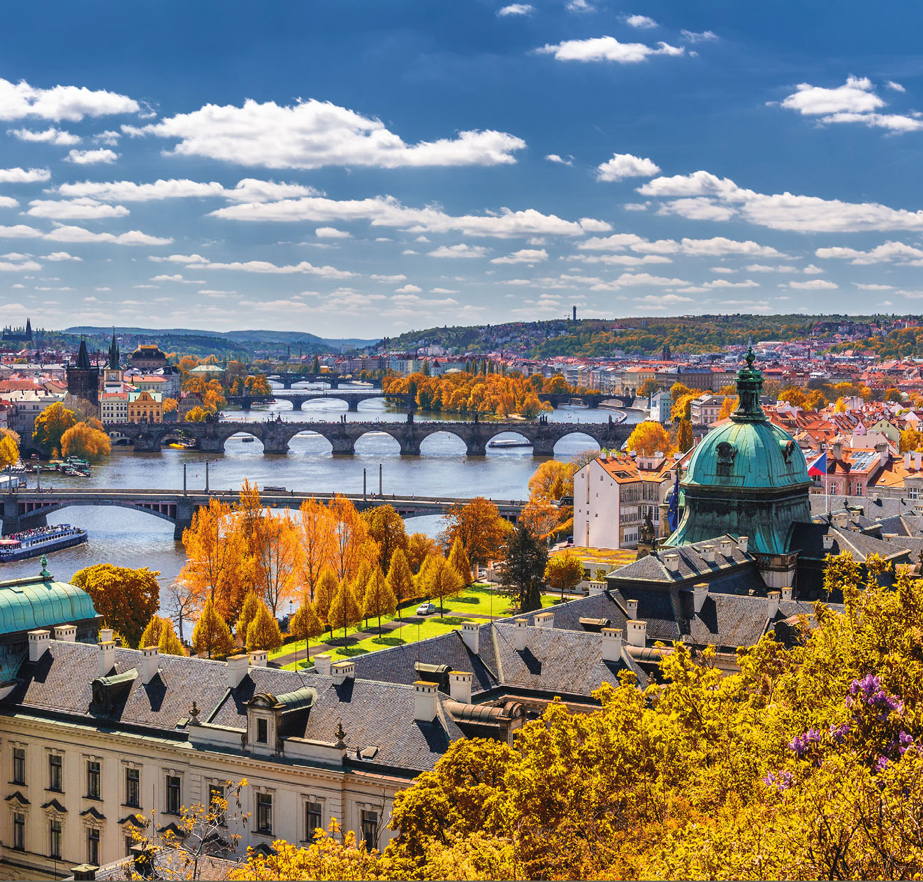 View to the historical bridges, Prague old town and Vltava river from popular view point in the Letna park (Letenske sady), beautiful autumn landscape in soft yellow light, Czech Republic