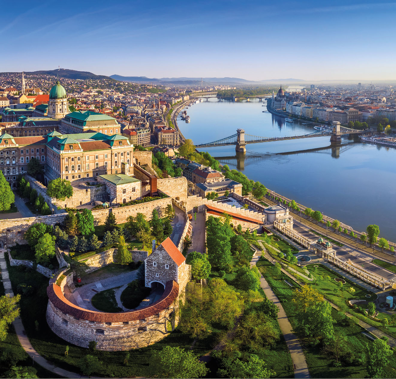 Budapest, Hungary - Aerial panoramic skyline view of Buda Castle Royal Palace with Szechenyi Chain Bridge, St.Stephen's Basilica, Hungarian Parliament and Matthias Church at sunrise with blue sky