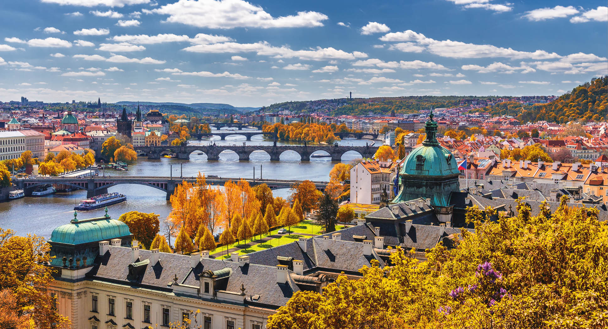 View to the historical bridges, Prague old town and Vltava river from popular view point in the Letna park (Letenske sady), beautiful autumn landscape in soft yellow light, Czech Republic