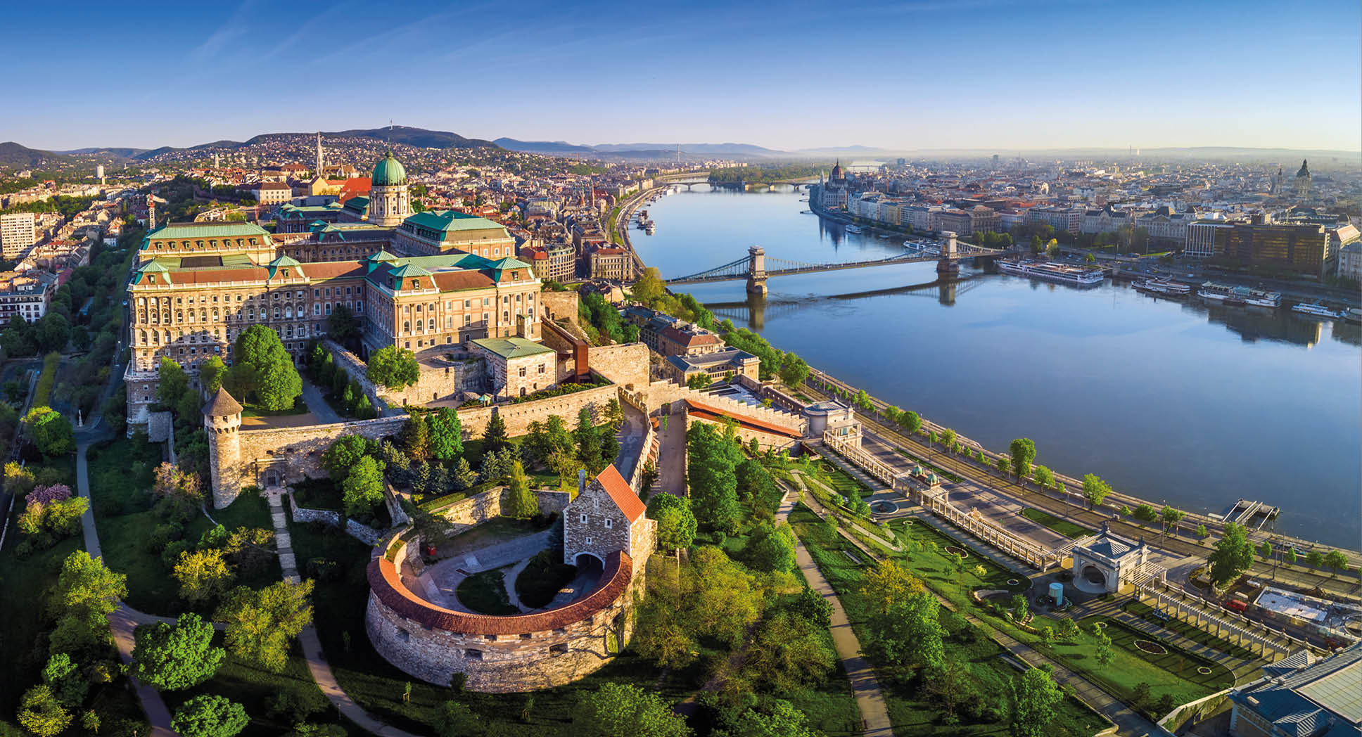 Budapest, Hungary - Aerial panoramic skyline view of Buda Castle Royal Palace with Szechenyi Chain Bridge, St.Stephen's Basilica, Hungarian Parliament and Matthias Church at sunrise with blue sky